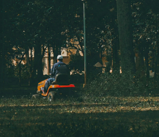Mitarbeiter auf einem Aufsitzmäher bei der professionellen Grünpflege einer Parkanlage.