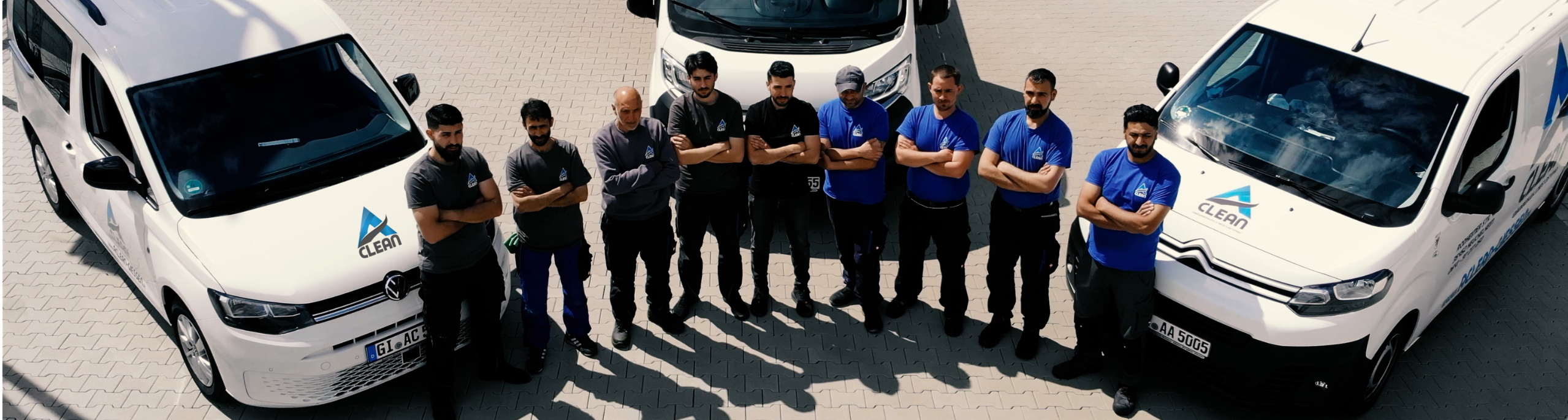 Das Team von A-Clean vor den Firmenfahrzeugen für Gebäudereinigung und Objektservice.